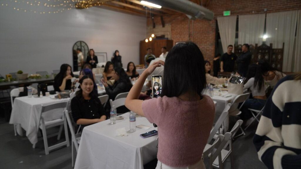 a young woman taking a picture of a group of people with her phone