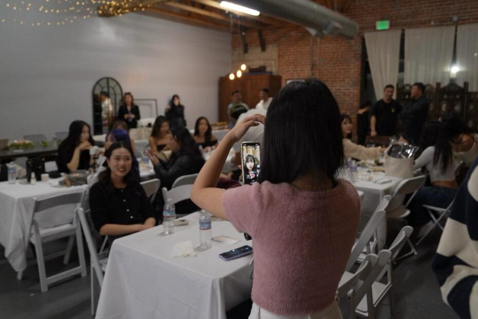 a young woman taking a picture of a group of people with her phone